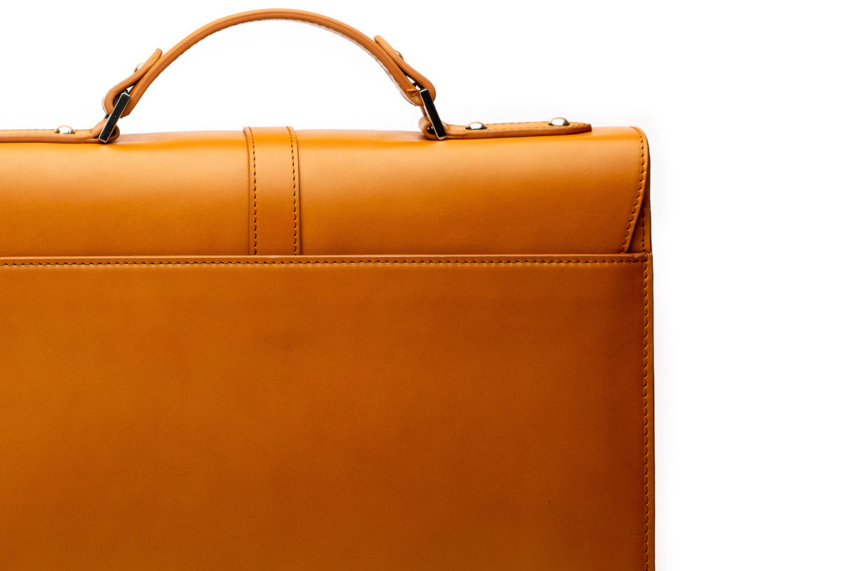 Tan leather briefcase lifestyle shot being carried by hand