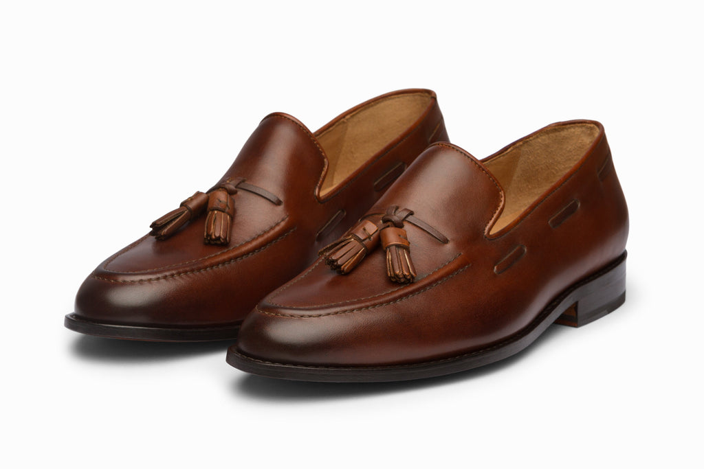 Brown tassel loafers three-quarter front view on white background